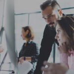 Image of people working around a computer for an article about marketing through a pandemic..